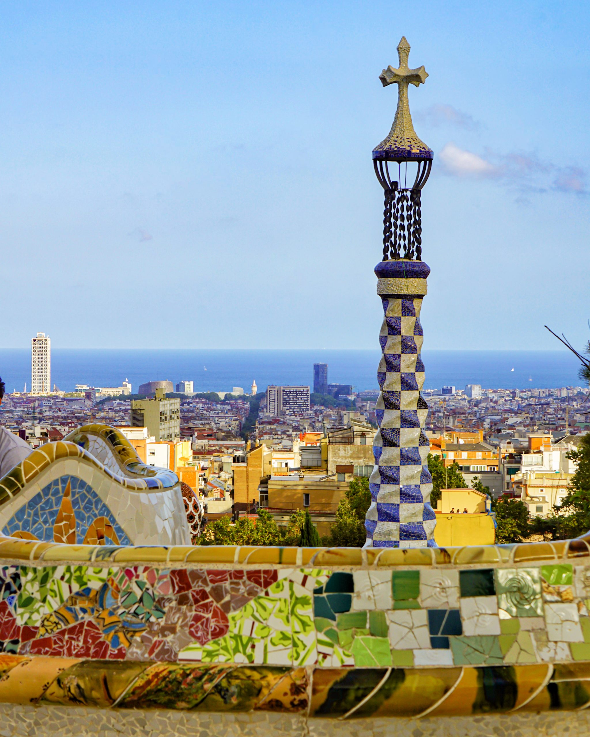 Mosaic tower at Park Guell with Barcelona and the sea behind it.