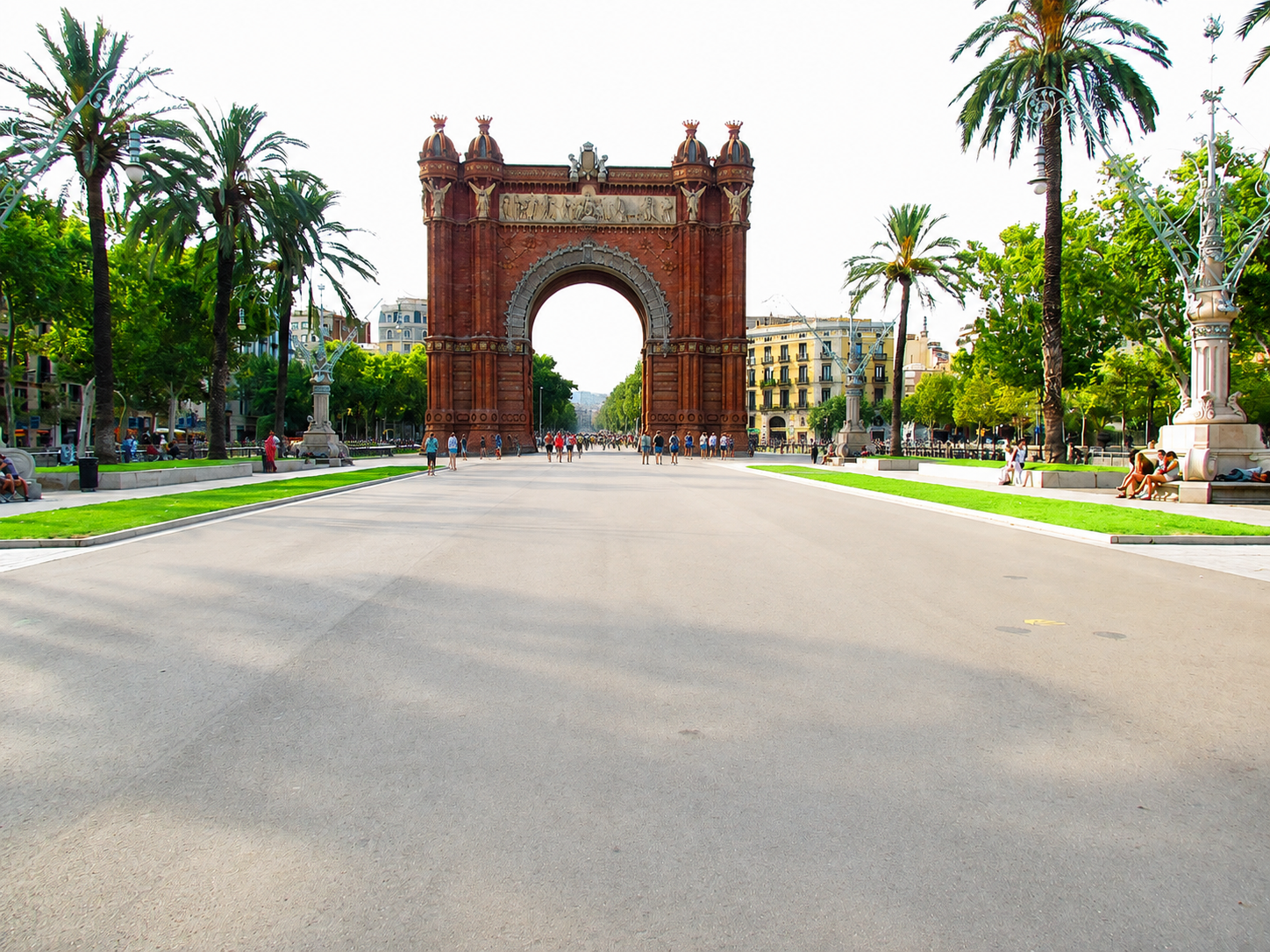 Wide view of Arc de Triomf from the palm-lined promenade.
